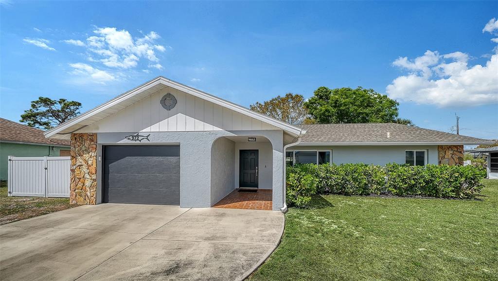A single-story house features a gray garage, a covered entryway, and a stone-accented facade — 972 LEEWARD ROAD, VENICE, FL
