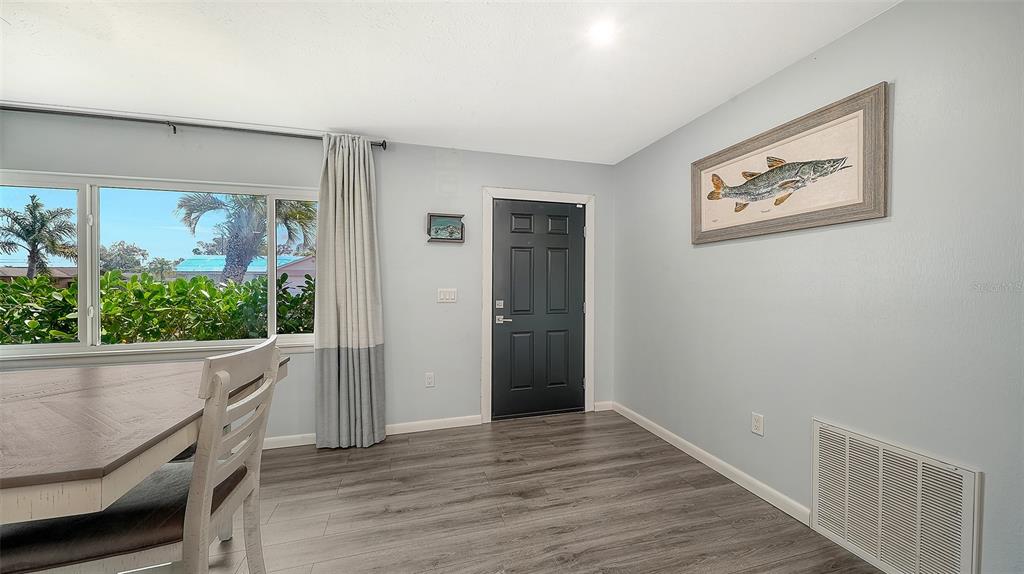A dining area features gray wood-look flooring, a dark door, and a framed fish print — 972 LEEWARD ROAD, VENICE, FL