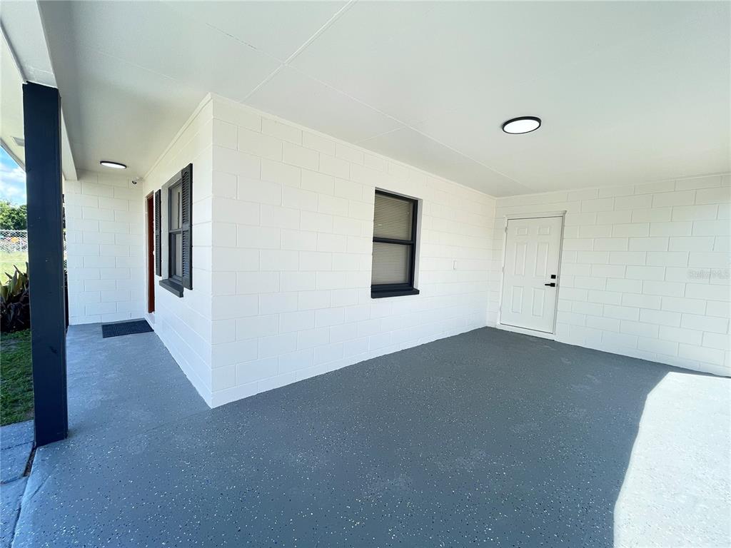 A covered patio with white concrete block walls, a gray speckled floor, and two doors — 2952 MORRIS DRIVE, BARTOW, FL