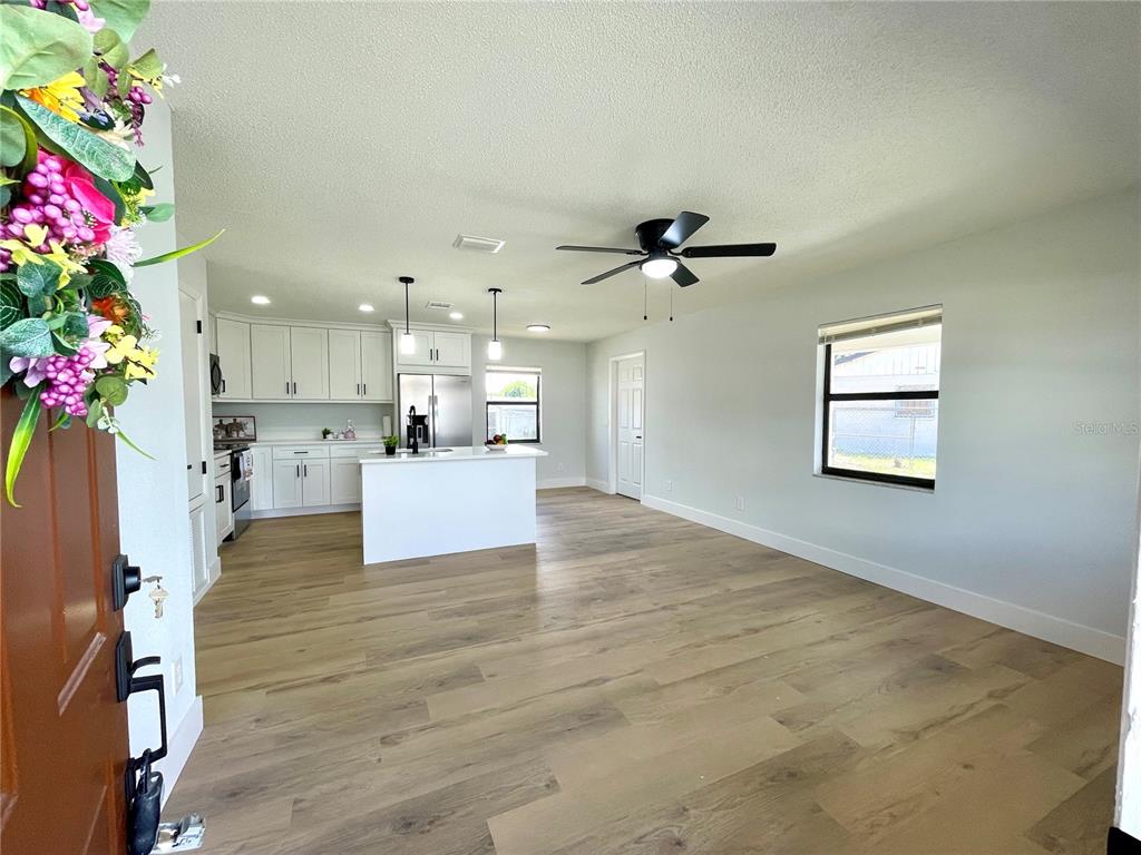 An open-concept kitchen and living area features white cabinetry, a center island, and wood flooring — 2952 MORRIS DRIVE, BARTOW, FL