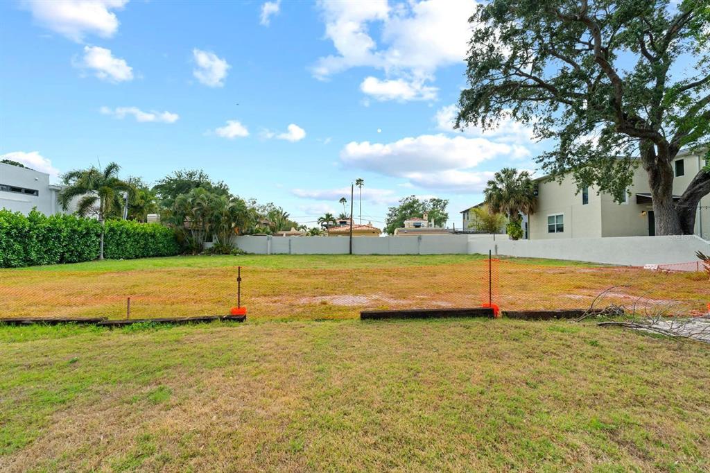 A vacant, grassy residential lot is enclosed by a low wall and orange construction fencing — 32 AEGEAN AVENUE, TAMPA, FL