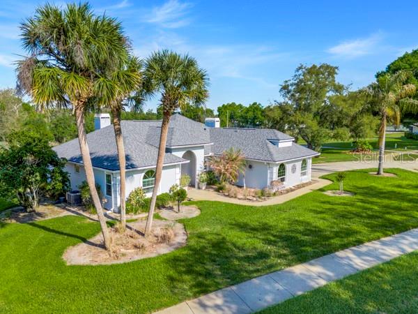 An aerial view of a light-colored single-story house with a gray roof and palm trees — 8739 AUGUSTA CT COURT, CLERMONT, FL