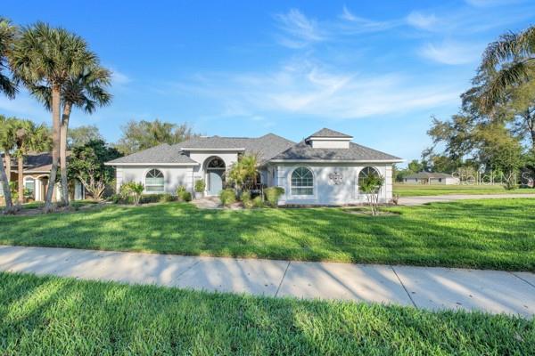 A single-story house with a gray roof and white exterior sits behind a grassy lawn — 8739 AUGUSTA CT COURT, CLERMONT, FL