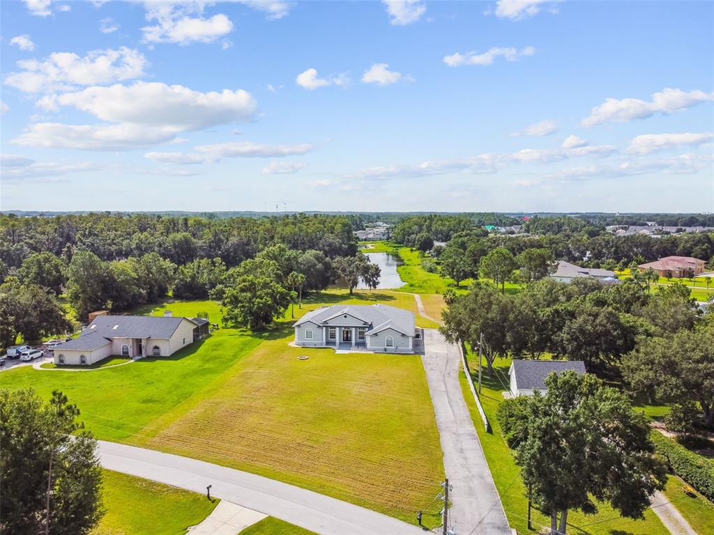 An aerial view shows a single-story house with a large lawn and a long driveway — 6644 COUNTRY CLUB ROAD, WESLEY CHAPEL, FL