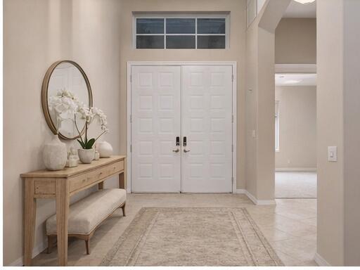 A bright entryway features a wooden console table, a round mirror, and double front doors — 12636 Via Ravenna, Boynton Beach FL 33436, BOYNTON BEACH, FL