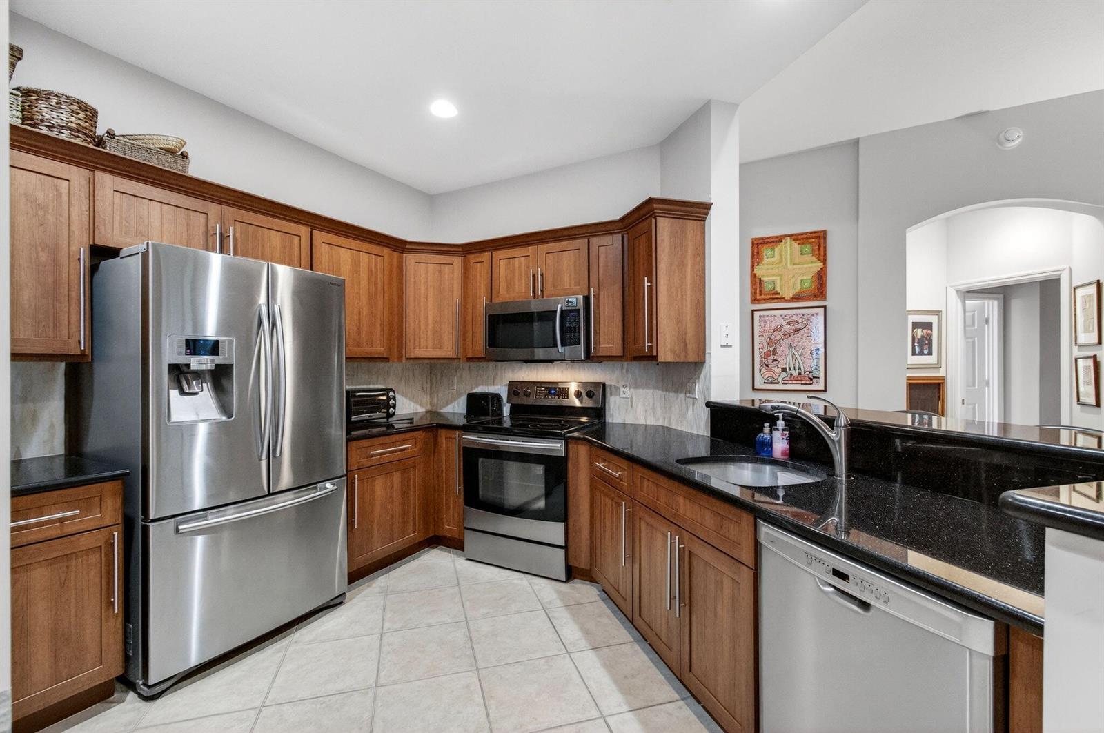 A kitchen features wood cabinets, stainless steel appliances, and black granite countertops — 12636 Via Ravenna, Boynton Beach FL 33436, BOYNTON BEACH, FL