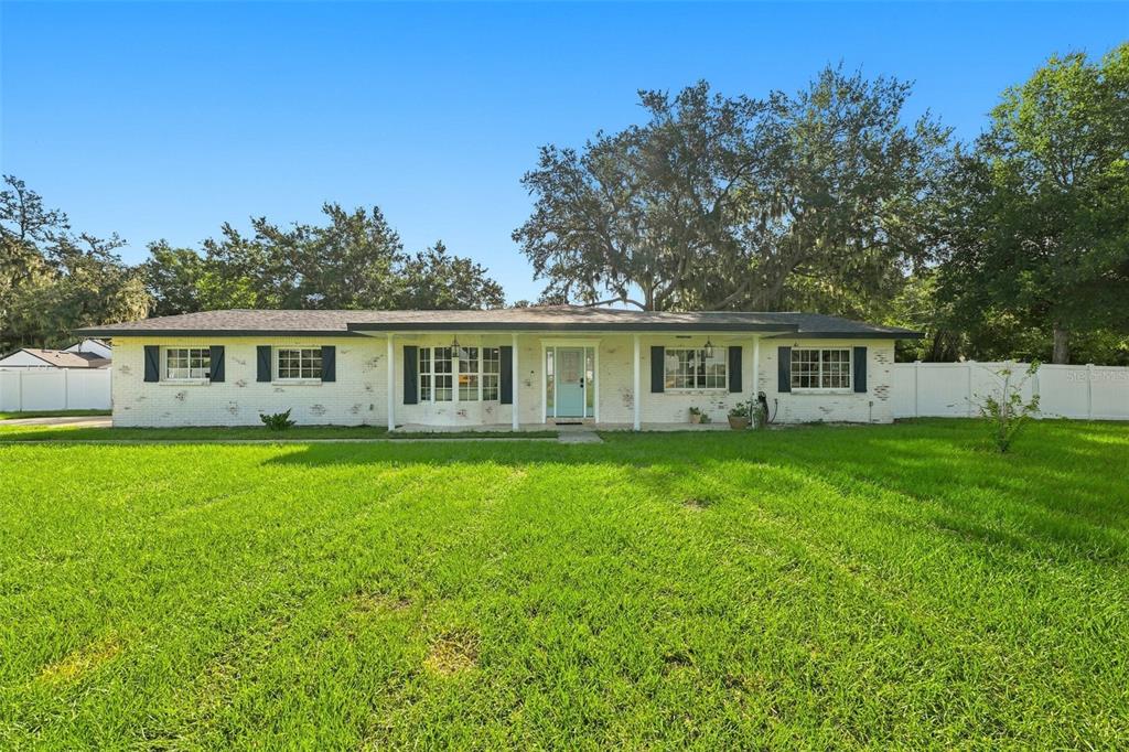 A single-story white brick house with black shutters and a light blue front door — 2119 GALLAGHER ROAD, DOVER, FL