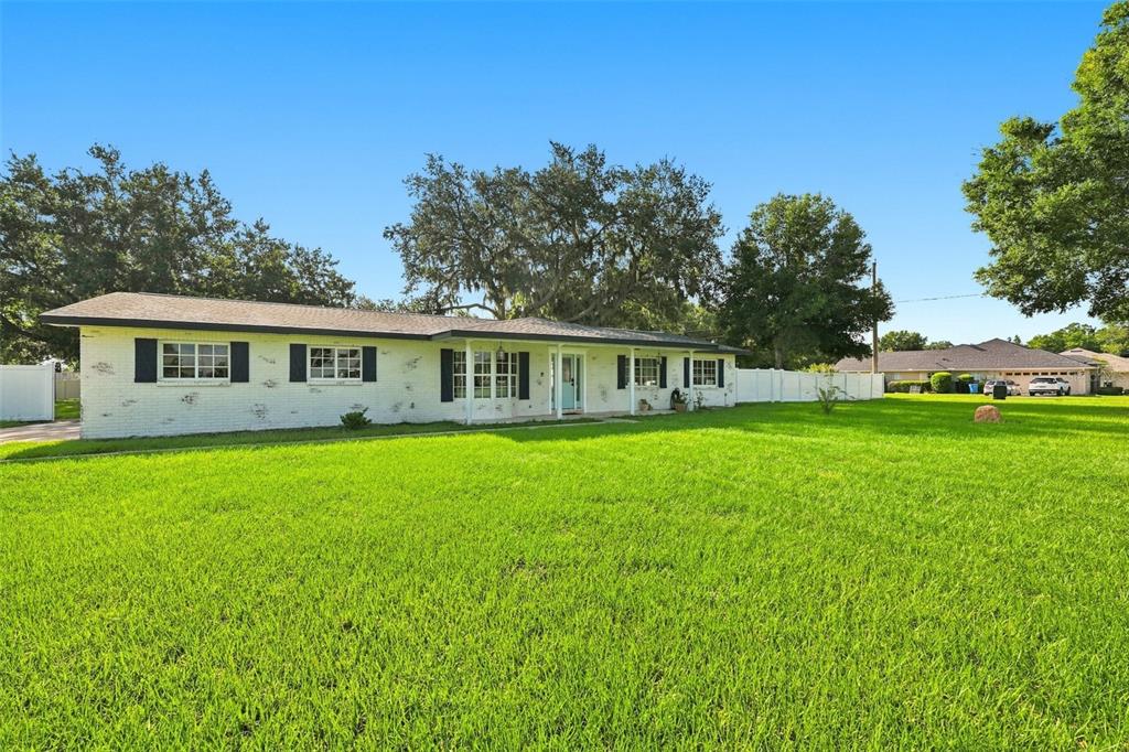 A single-story white brick house with black shutters sits on a large, grassy lawn — 2119 GALLAGHER ROAD, DOVER, FL