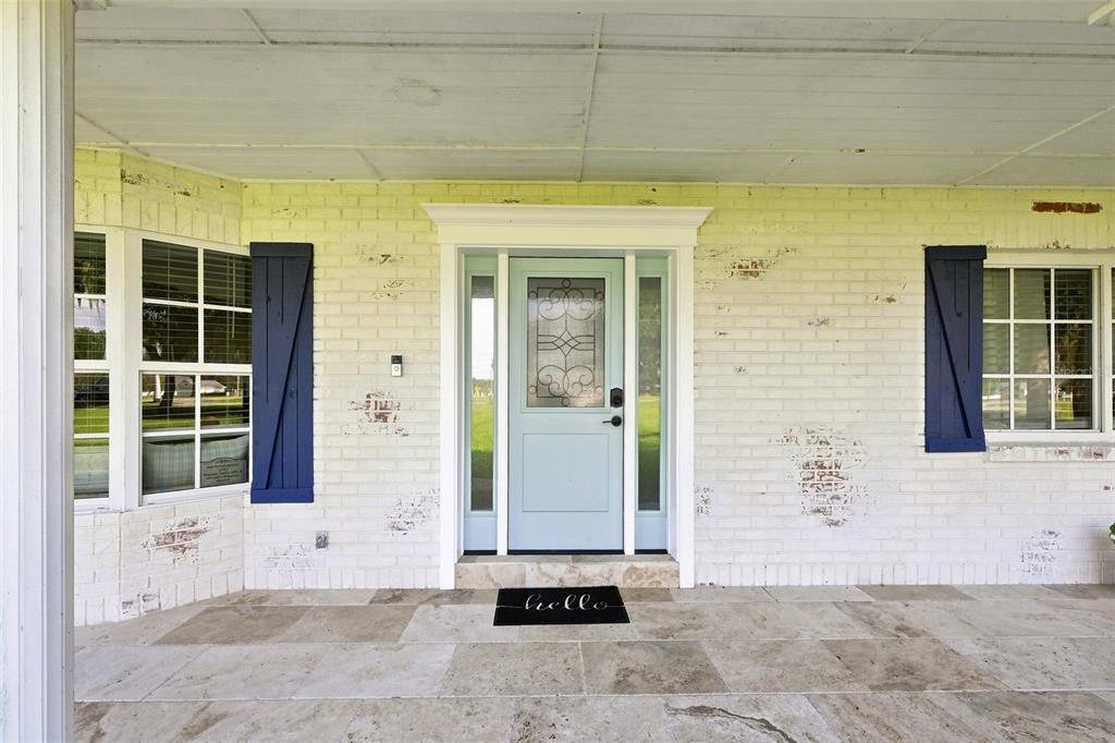 A front porch with a light blue door, white brick walls, and dark blue shutters — 2119 GALLAGHER ROAD, DOVER, FL