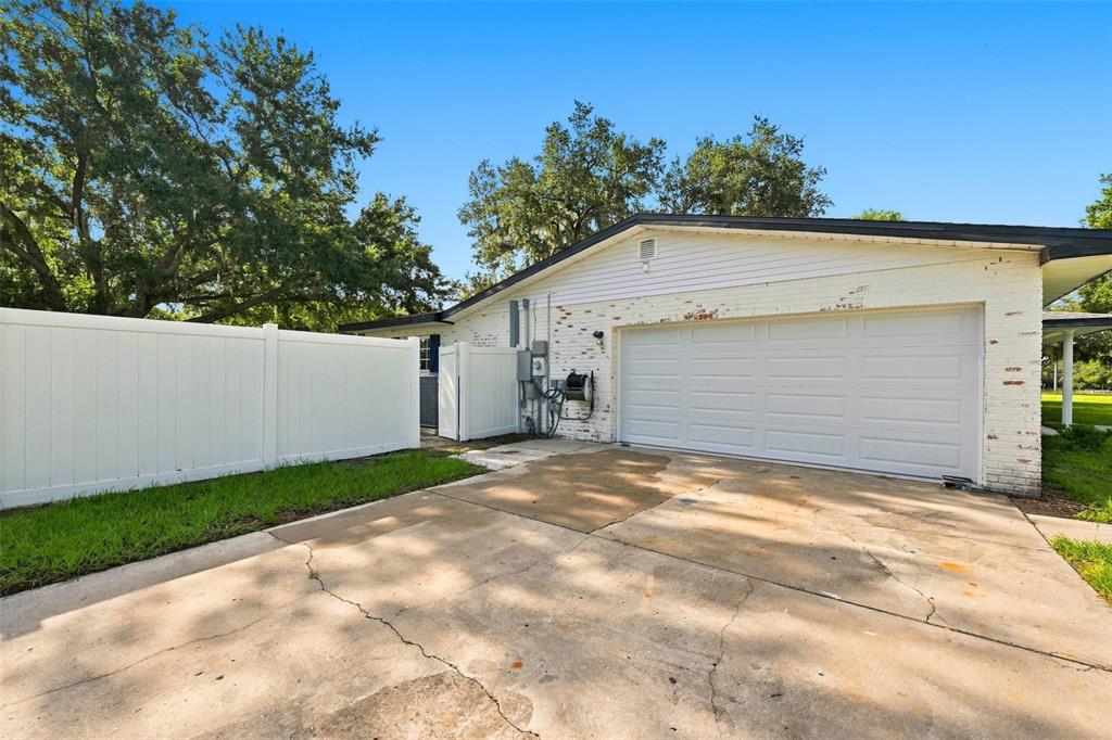 A white brick garage with a white vinyl fence and a concrete driveway outside — 2119 GALLAGHER ROAD, DOVER, FL