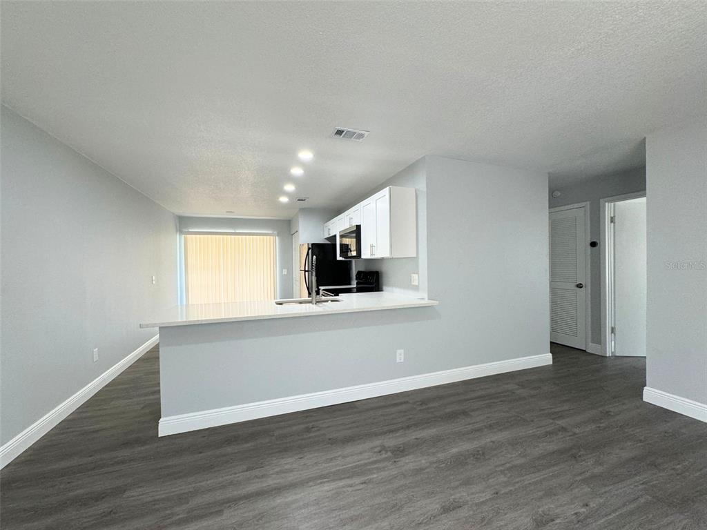 A kitchen with white cabinets and a breakfast bar overlooks a living area — 440 S HILL AVENUE, DELAND, FL