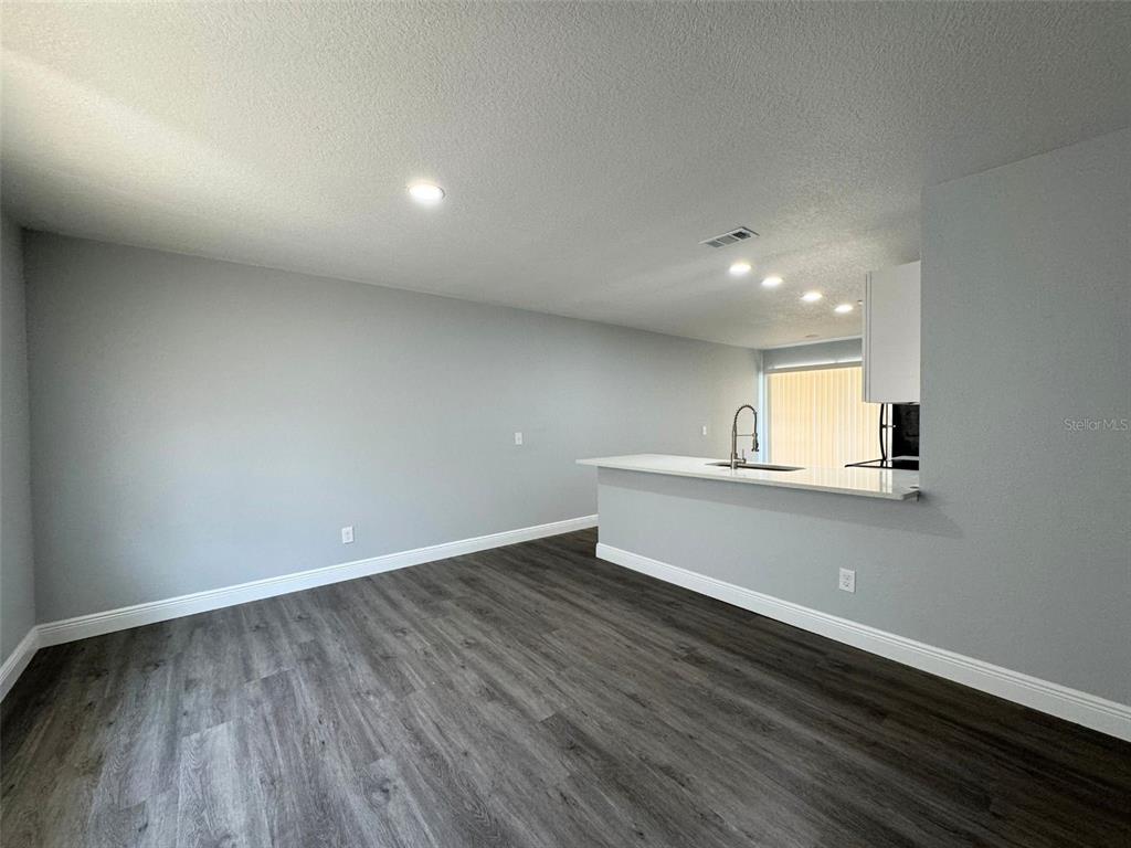 A room with gray walls, dark wood-look flooring, and a kitchen breakfast bar — 440 S HILL AVENUE, DELAND, FL