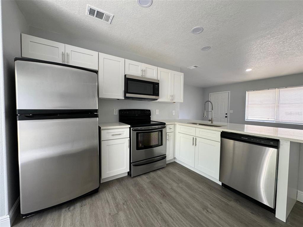 A kitchen features white cabinets, stainless steel appliances, and light-colored countertops — 440 S HILL AVENUE, DELAND, FL