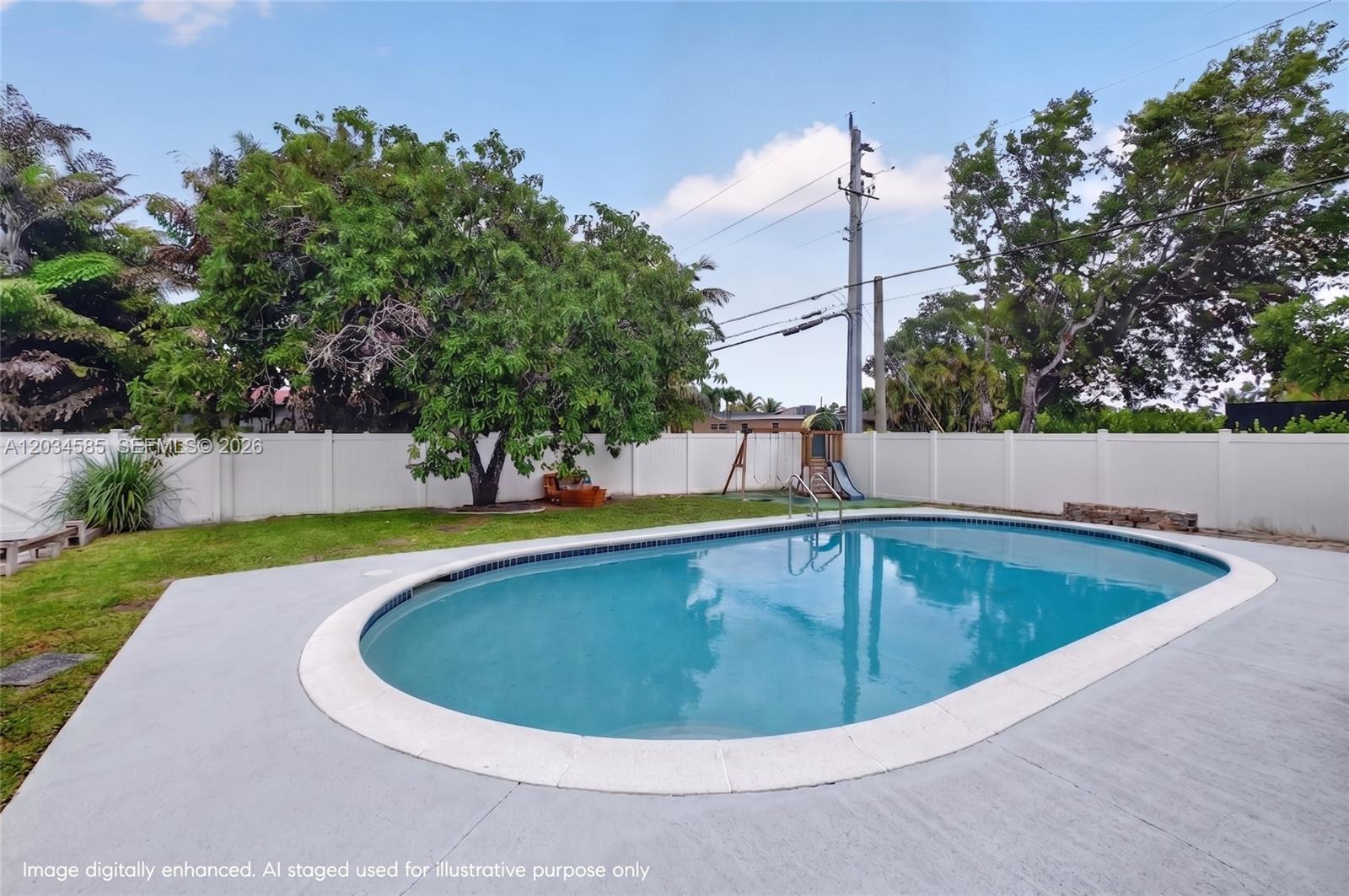 A backyard features an oval swimming pool, a grassy lawn, and a white privacy fence — 1901 N 56th Ave, Hollywood FL 33021, HOLLYWOOD, FL