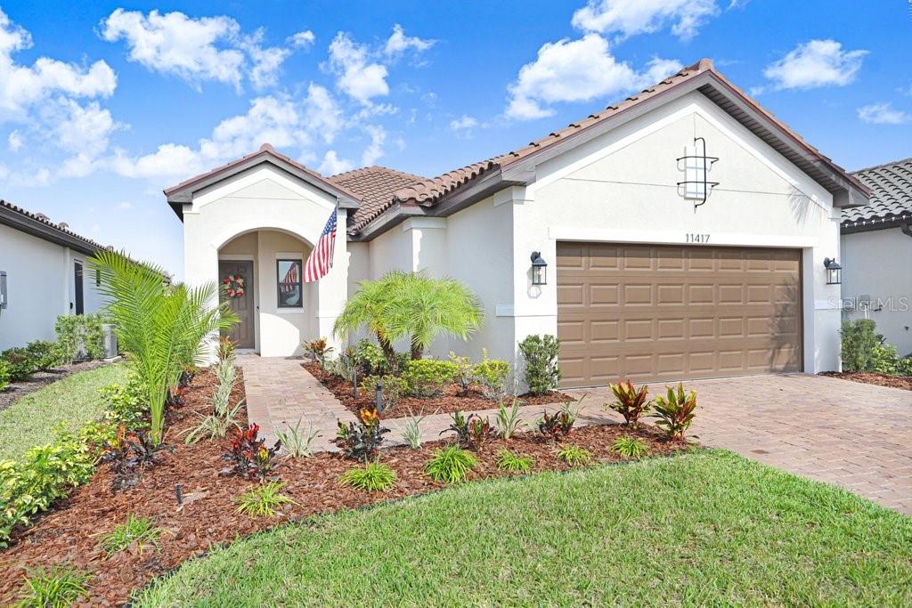 A single-story house with a brown garage door, a paved walkway, and landscaped front yard — 11417 TRIVIO TERRACE, PALMETTO, FL