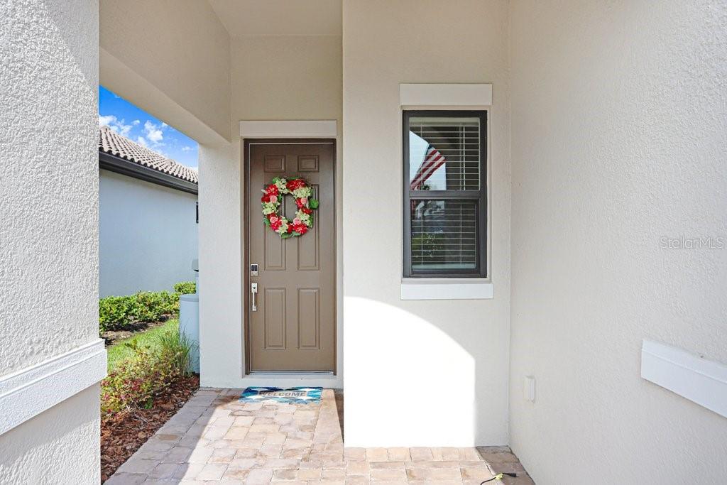A front entryway features a brown door with a wreath and a small window — 11417 TRIVIO TERRACE, PALMETTO, FL