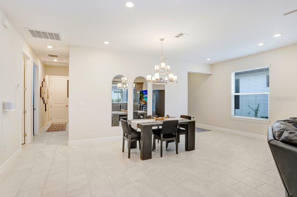 A dining room with tile flooring, a chandelier, and arched mirrors on the back wall — 11417 TRIVIO TERRACE, PALMETTO, FL