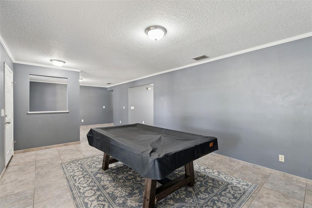 A room with gray walls, tiled floors, and a pool table under a ceiling light — 1804 VALE DRIVE, CLERMONT, FL