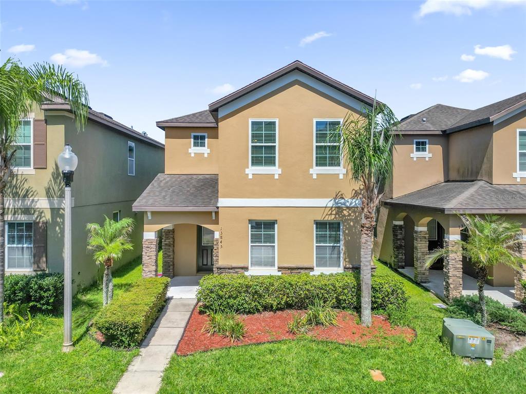 A two-story tan house with stone accents, a front walkway, and a landscaped yard — 13845 BRIDGEWATER CROSSINGS BLVD, WINDERMERE, FL