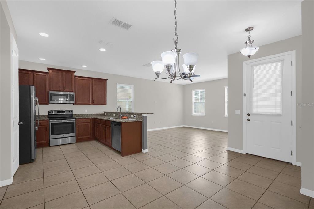 An open-concept kitchen and dining area features dark wood cabinets, granite countertops, and tile flooring — 13845 BRIDGEWATER CROSSINGS BLVD, WINDERMERE, FL