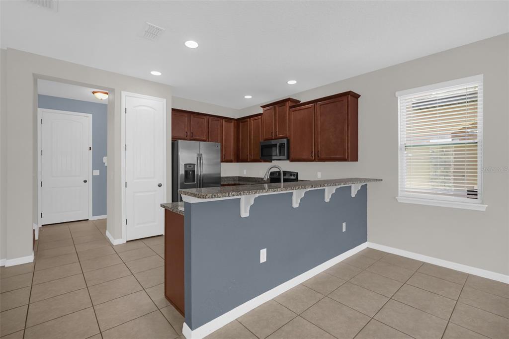 A kitchen features dark wood cabinets, stainless steel appliances, and a gray breakfast bar island — 13845 BRIDGEWATER CROSSINGS BLVD, WINDERMERE, FL