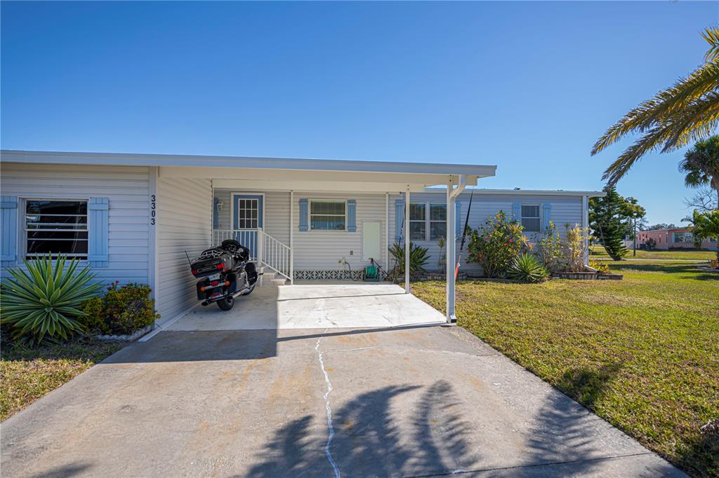 A single-story house with light siding, a carport, and a motorcycle parked in the driveway — 3303 BLUE JAY LANE, ENGLEWOOD, FL