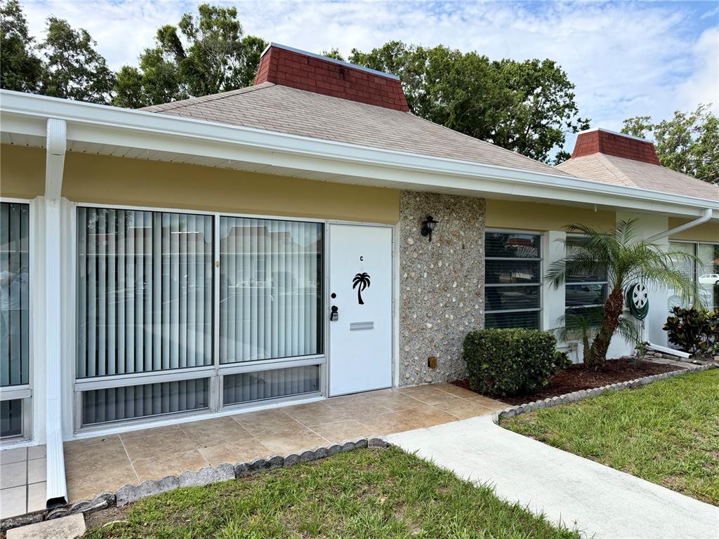 A single-story residential unit with a white door, large windows, and a stone-accented exterior — 4313 TAHITIAN GARDENS CIRCLE UNIT C, HOLIDAY, FL