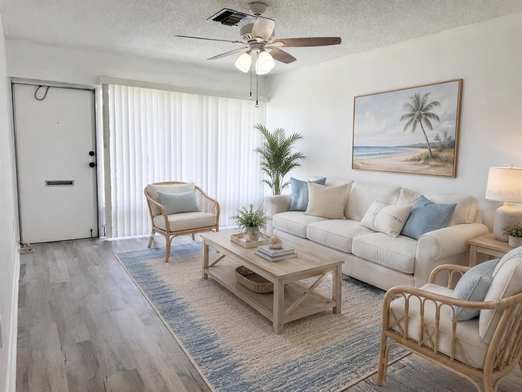 A living room features a white sofa, two rattan chairs, a coffee table, and area rug — 4313 TAHITIAN GARDENS CIRCLE UNIT C, HOLIDAY, FL