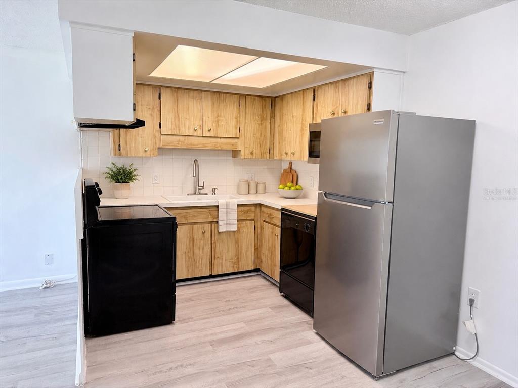 A kitchen features light wood cabinets, stainless steel appliances, and light-colored flooring — 4313 TAHITIAN GARDENS CIRCLE UNIT C, HOLIDAY, FL