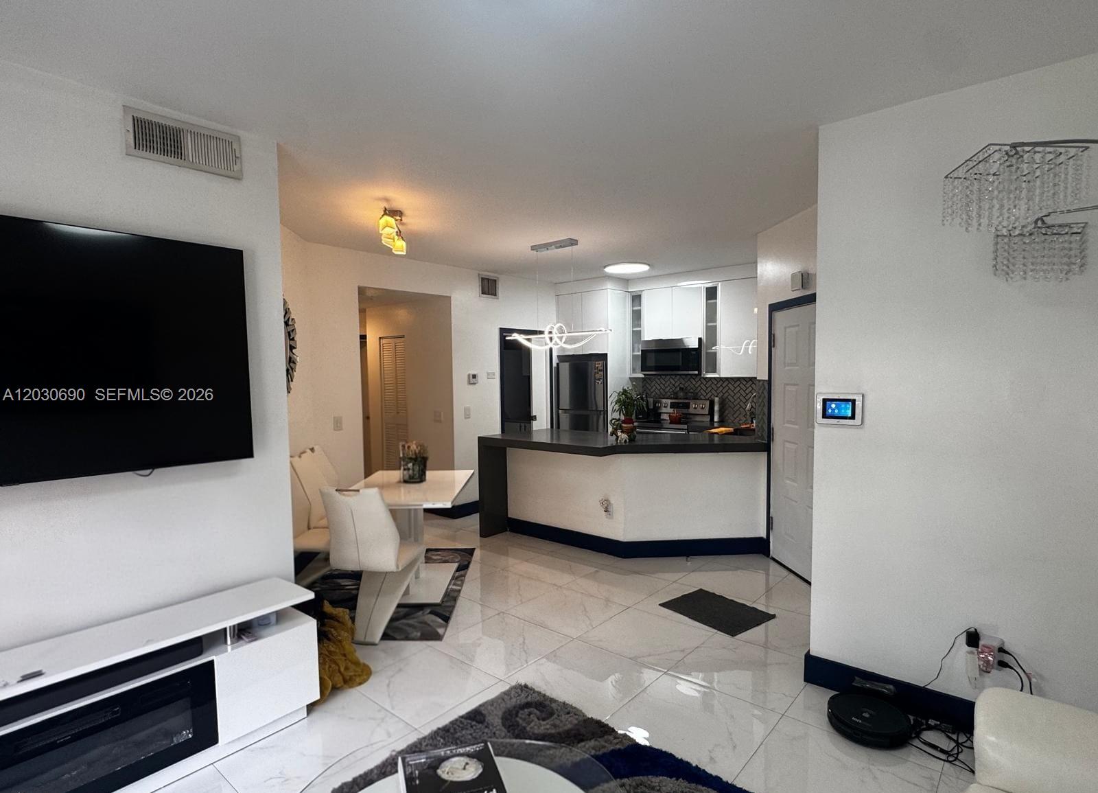 A living room and dining area open to a kitchen with white cabinets and counters — 18306 NW 68th Ave # A, Hialeah FL 33015, HIALEAH, FL