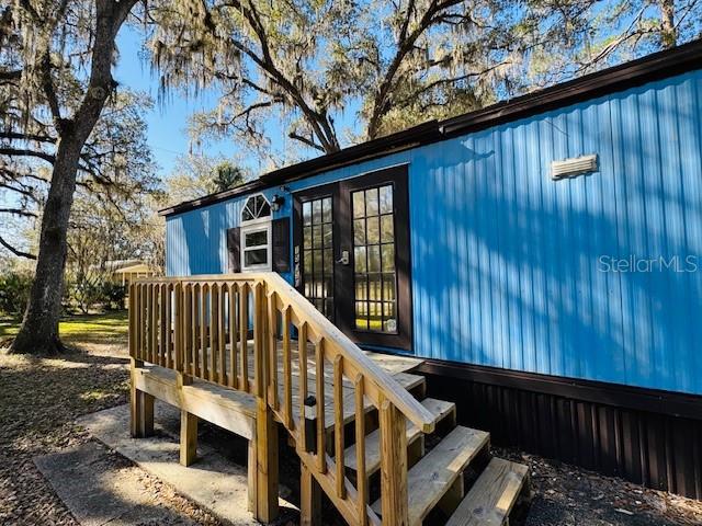 A blue mobile home exterior features a wooden staircase leading to a glass-paned door — 15050 NE 113TH COURT, FORT MC COY, FL