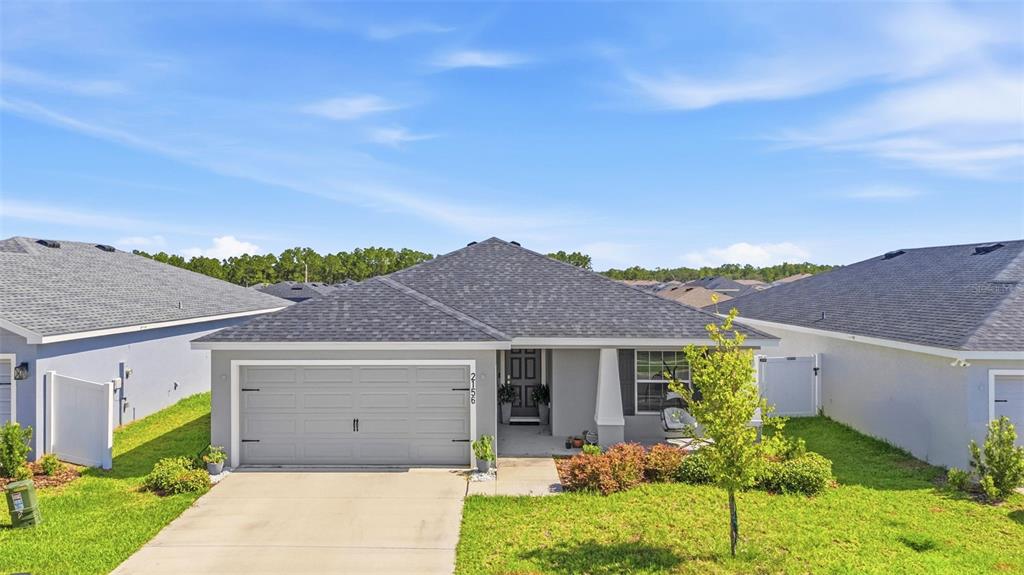 A single-story suburban house with a gray exterior, a two-car garage, and a shingled roof — 2156 DESERT ROSE DRIVE, DAVENPORT, FL