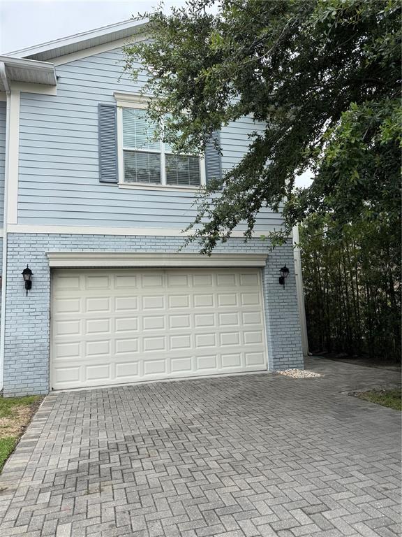 A two-story house with light blue siding, a brick lower level, and a paved driveway — 606 S LINCOLN AVENUE UNIT 3, TAMPA, FL