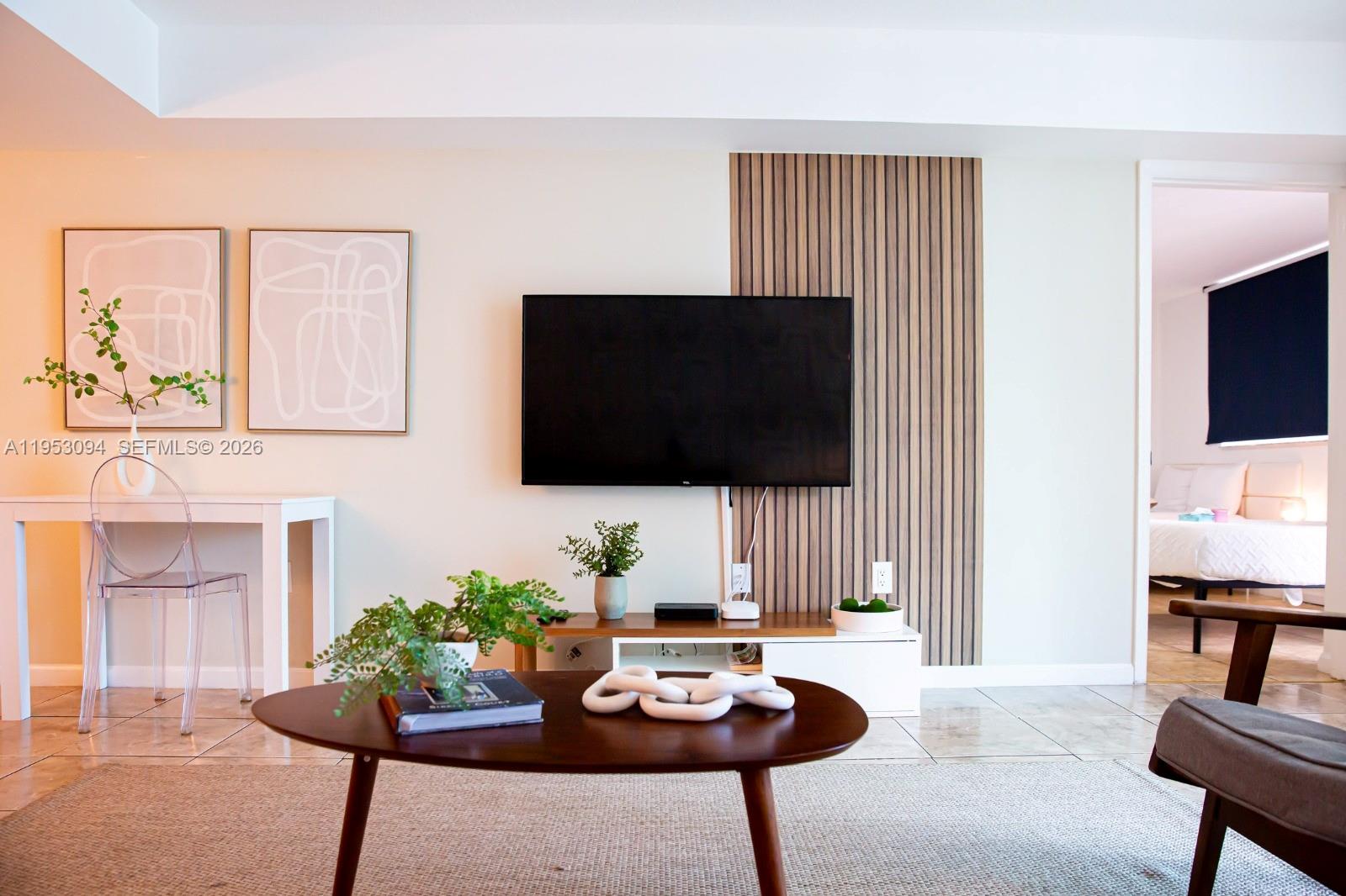 A living room features a wall-mounted television, a wood-slat accent panel, and a coffee table — 1200 Brickell Bay Dr # 3215, Miami FL 33131, MIAMI, FL