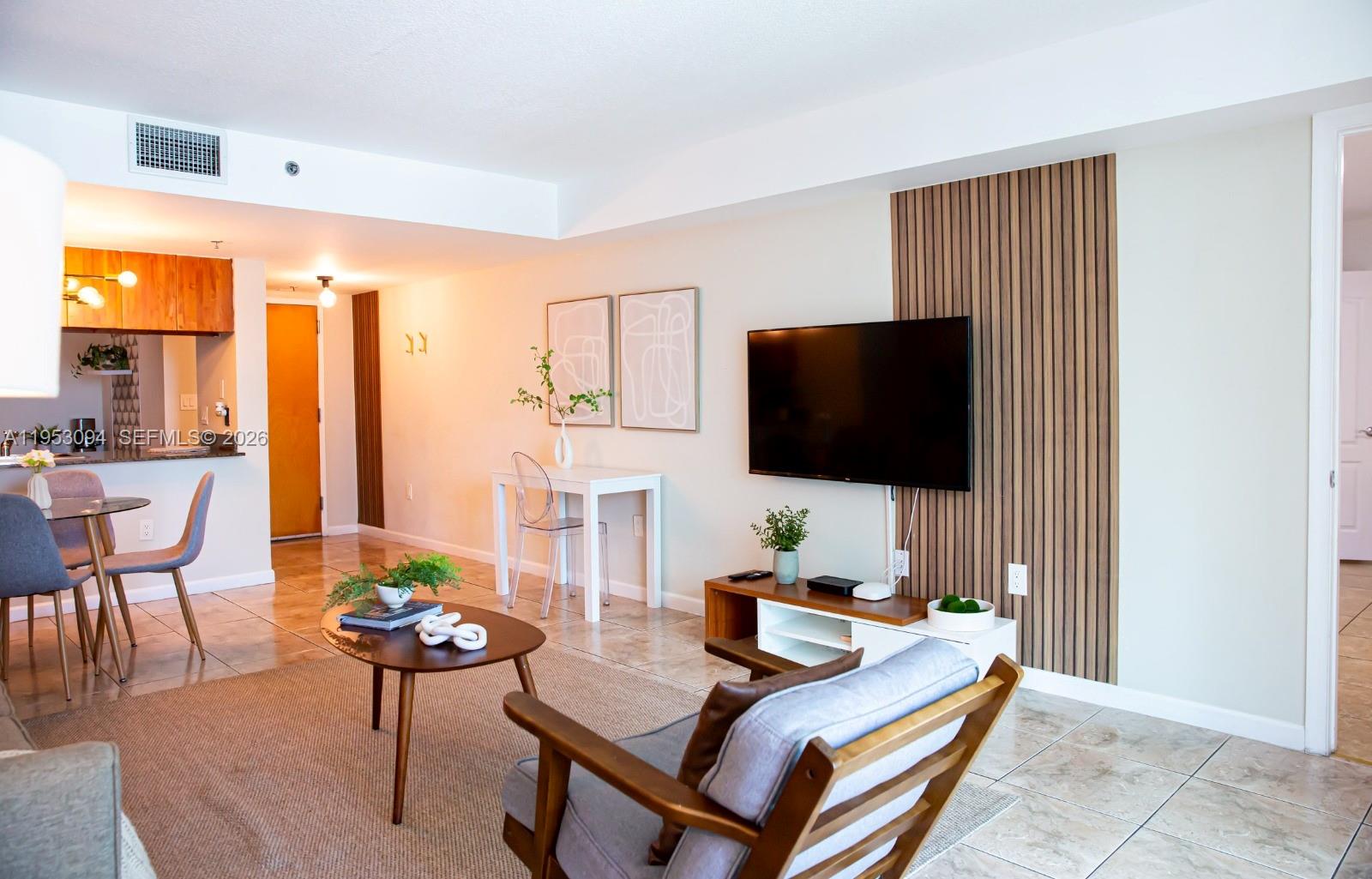 A living room features a wood-slat accent wall, a wall-mounted television, and tile flooring — 1200 Brickell Bay Dr # 3215, Miami FL 33131, MIAMI, FL