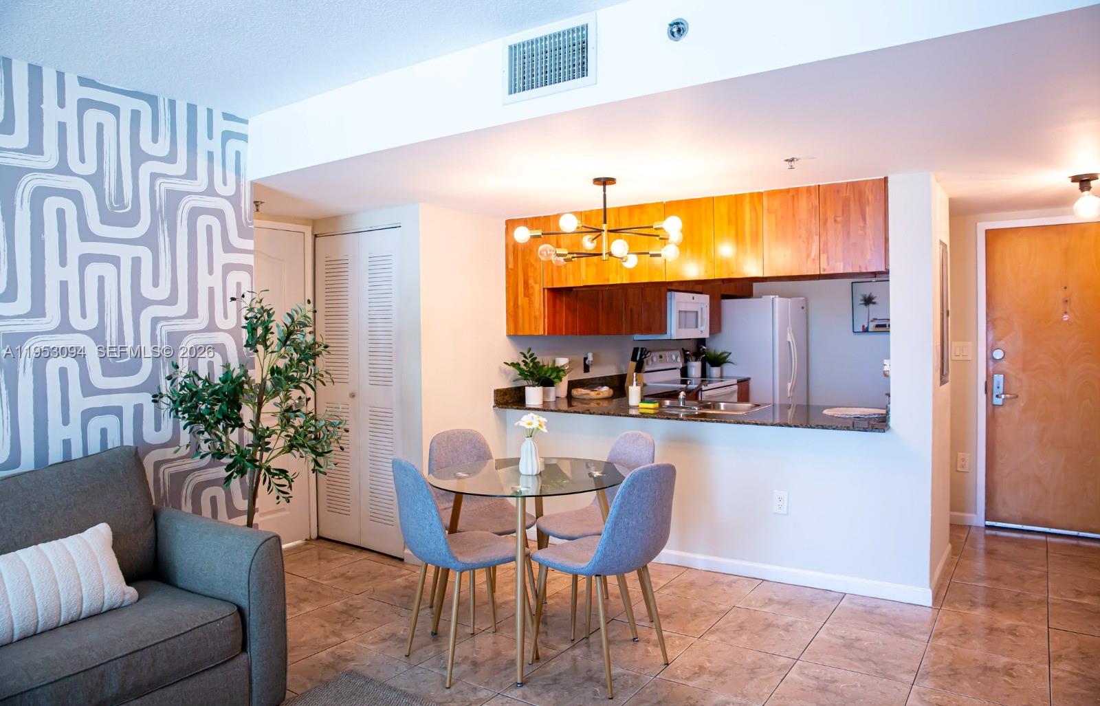 A dining area with a glass table and chairs sits before an open kitchen — 1200 Brickell Bay Dr # 3215, Miami FL 33131, MIAMI, FL