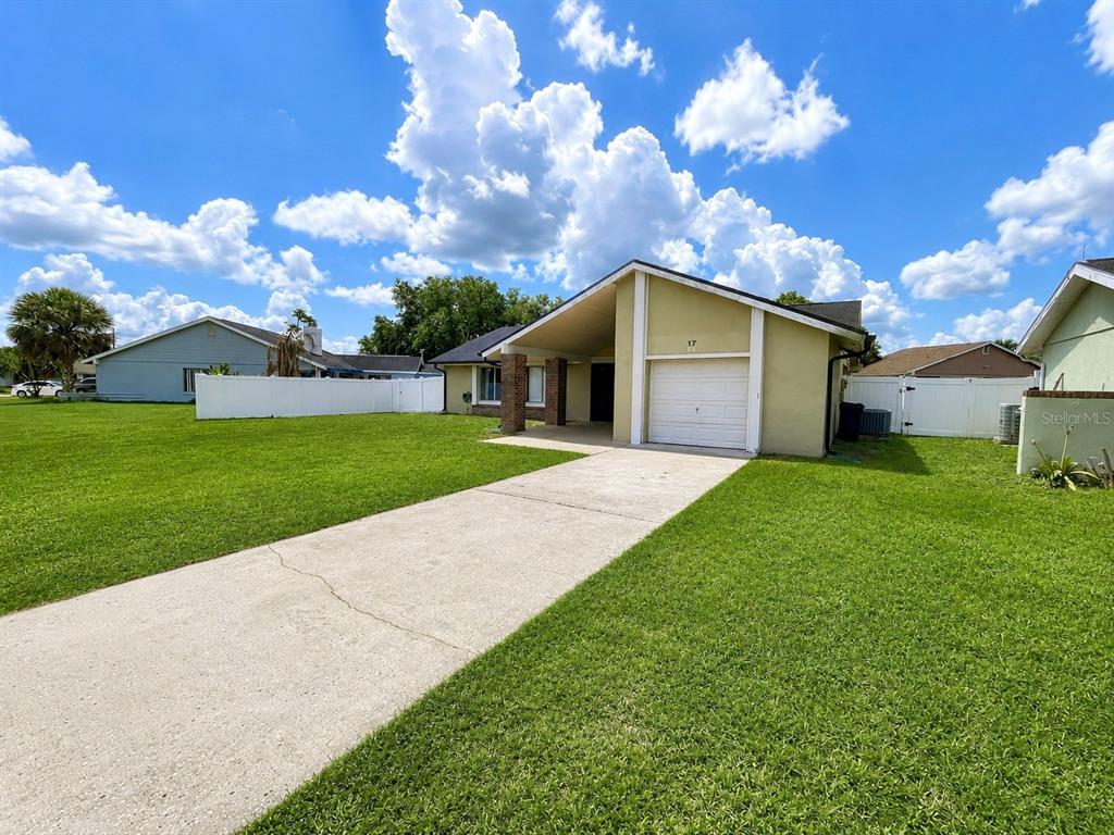 A single-story house with a white garage door, a concrete driveway, and a grassy lawn — 17 S FLAG DRIVE, KISSIMMEE, FL