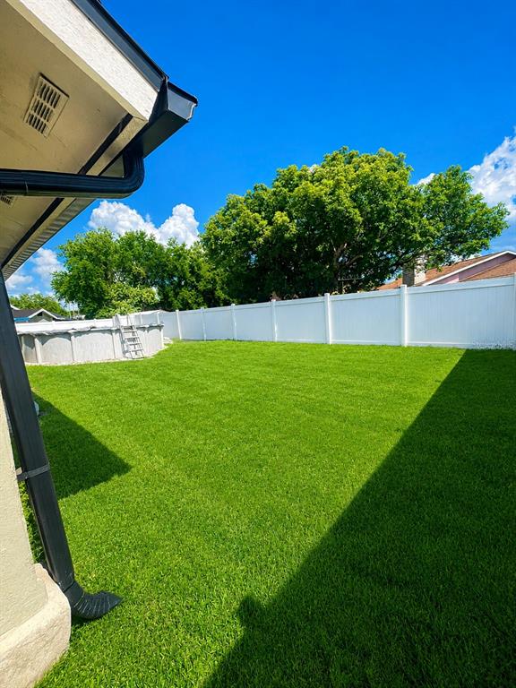 A backyard features a green lawn, a white vinyl fence, and an above-ground pool — 17 S FLAG DRIVE, KISSIMMEE, FL