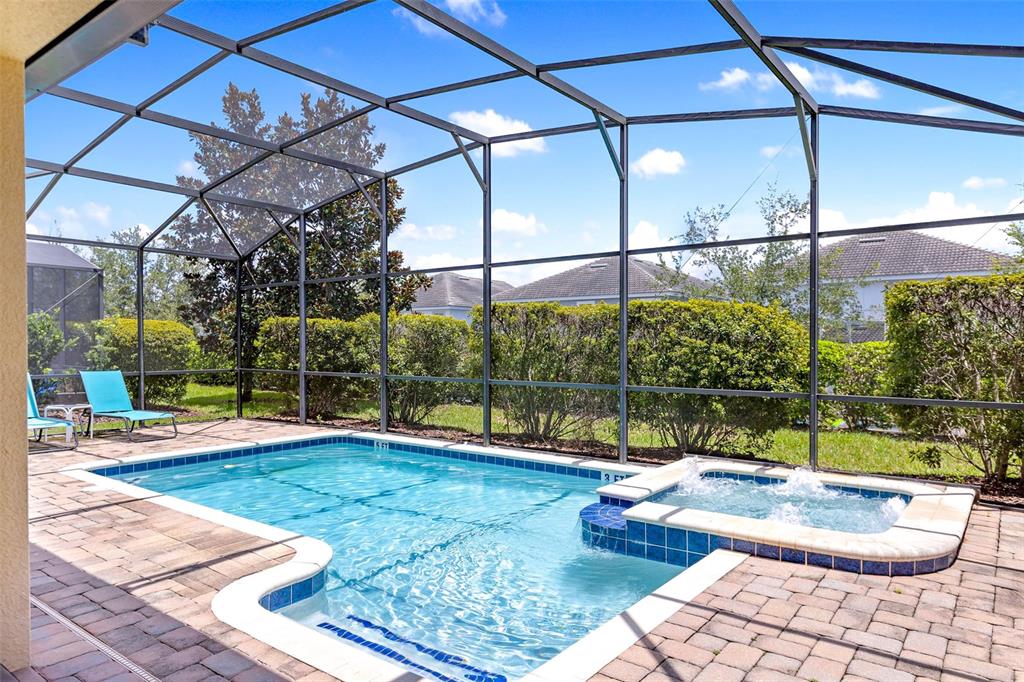 A screened-in swimming pool and attached hot tub on a paved patio with landscaping — 9023 SHADOW MOUNTAIN STREET, DAVENPORT, FL