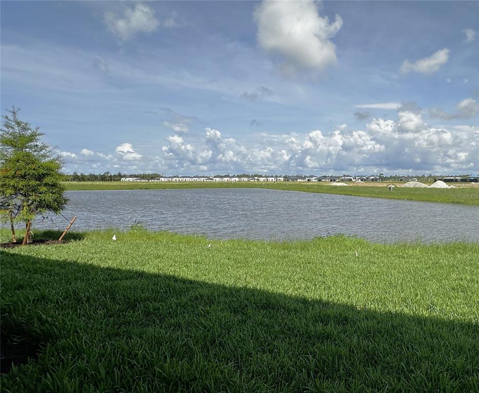 A view of a retention pond and grassy lawn under a partly cloudy sky — 28521 SWEET MEADOW DRIVE, PUNTA GORDA, FL
