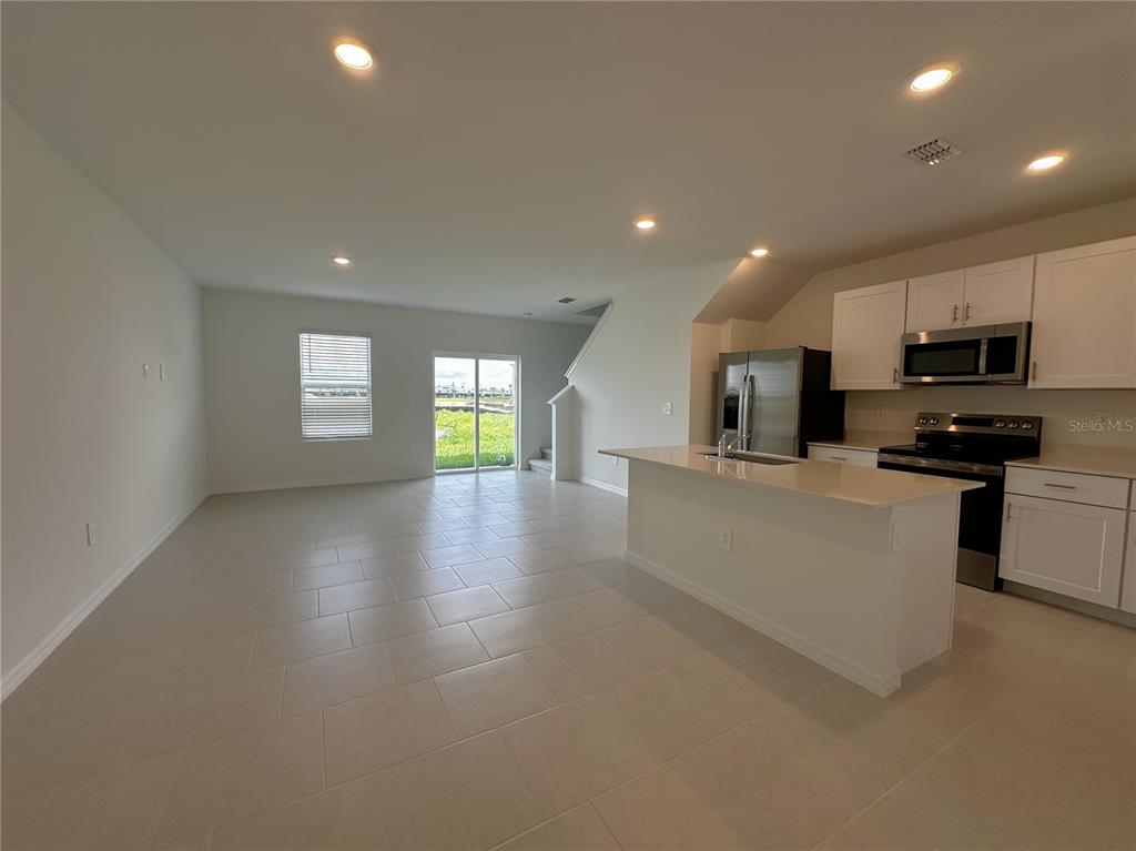 An open-concept kitchen and living area features white cabinetry, stainless steel appliances, and tile flooring — 28521 SWEET MEADOW DRIVE, PUNTA GORDA, FL