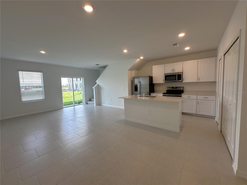 An open-concept kitchen and living area features white cabinets, stainless steel appliances, and tile flooring — 28521 SWEET MEADOW DRIVE, PUNTA GORDA, FL