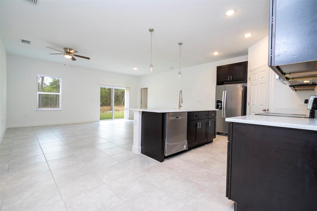 A kitchen with dark cabinets and a center island overlooks an open living area — 15315 SW 50TH AVENUE ROAD, OCALA, FL