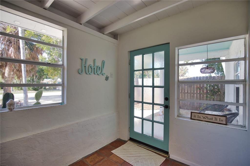 A sunroom features terracotta tile floors, a teal door, and a sign reading Hotel — 650 EDWARDS STREET, ENGLEWOOD, FL