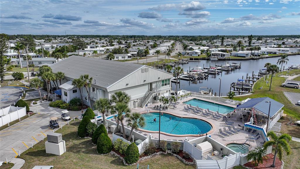 An aerial view shows a community building with a pool, hot tub, and boat docks — 553 FLEETWOOD STREET, NORTH PORT, FL