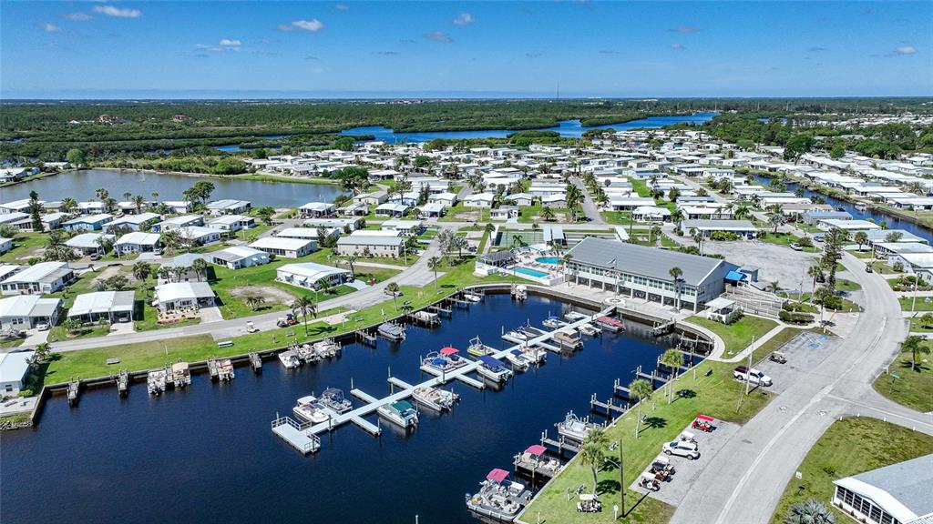 An aerial view shows a residential community with a marina, boat slips, and a clubhouse — 553 FLEETWOOD STREET, NORTH PORT, FL