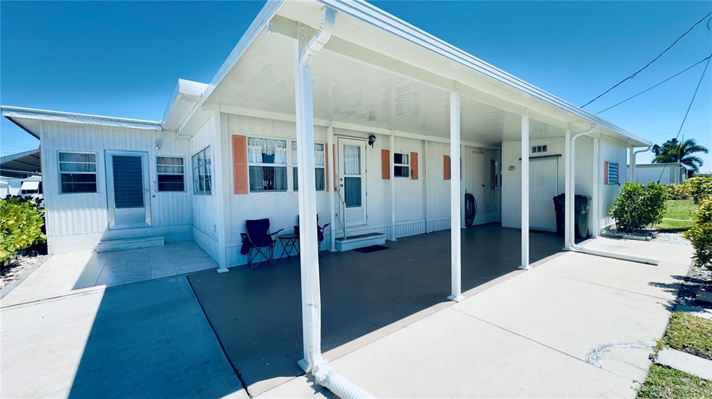 A white mobile home features a covered carport, a concrete patio, and orange window shutters — 553 FLEETWOOD STREET, NORTH PORT, FL