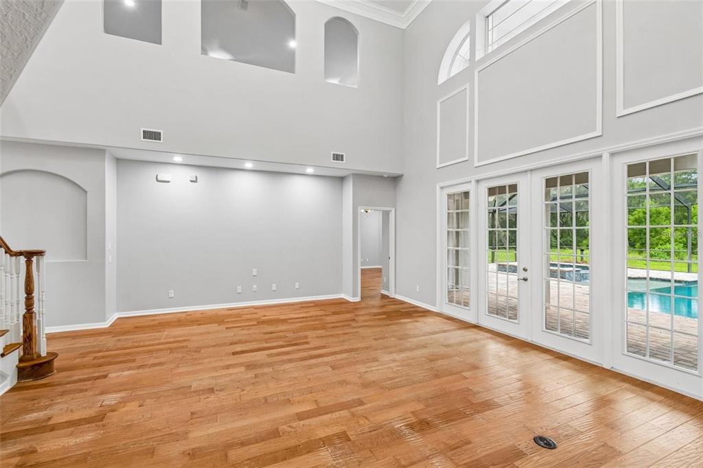 A living room with hardwood floors, a large staircase, and an open kitchen in back — 18326 SUCCESS ROAD, BROOKSVILLE, FL