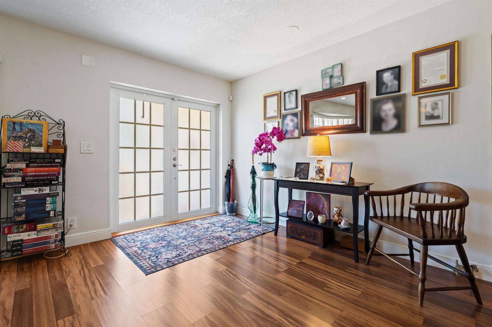 An entryway features a glass-paned double door, wood flooring, a console table, and wall-mounted photos — 4921 Jackson Street, Hollywood FL 33021, HOLLYWOOD, FL