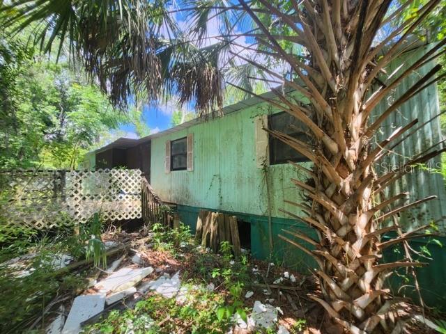 A weathered, light green mobile home sits in a wooded area with a palm tree — 3140 NE 162ND PLACE, CITRA, FL